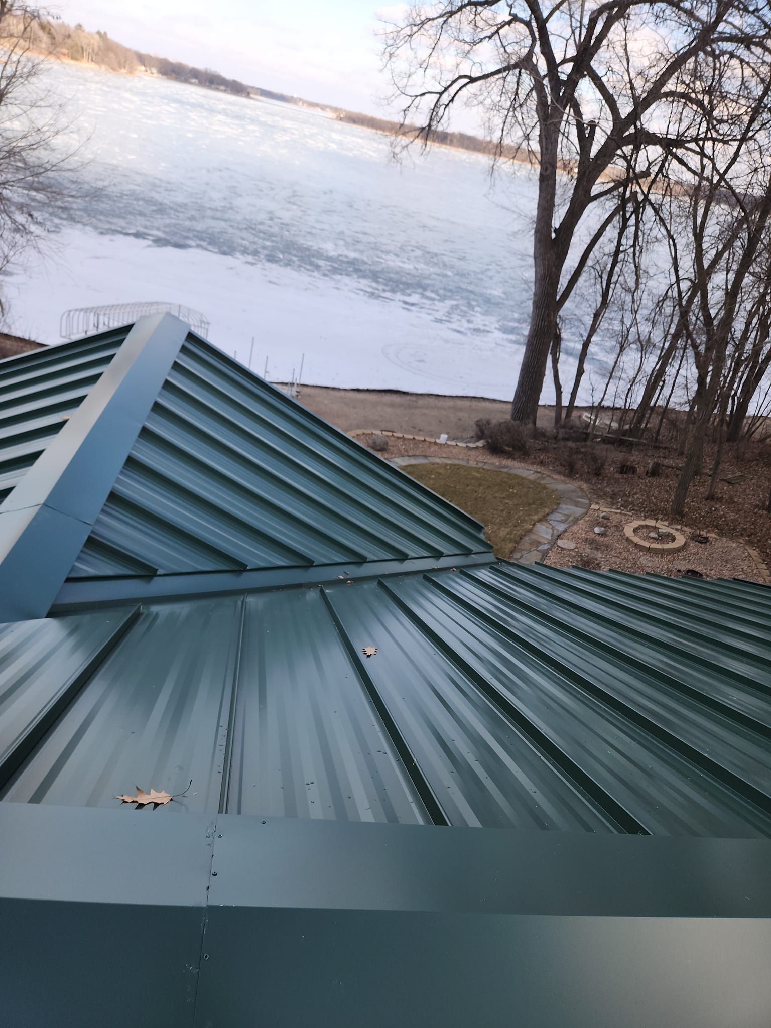 A green metal roof with a view of a lake.