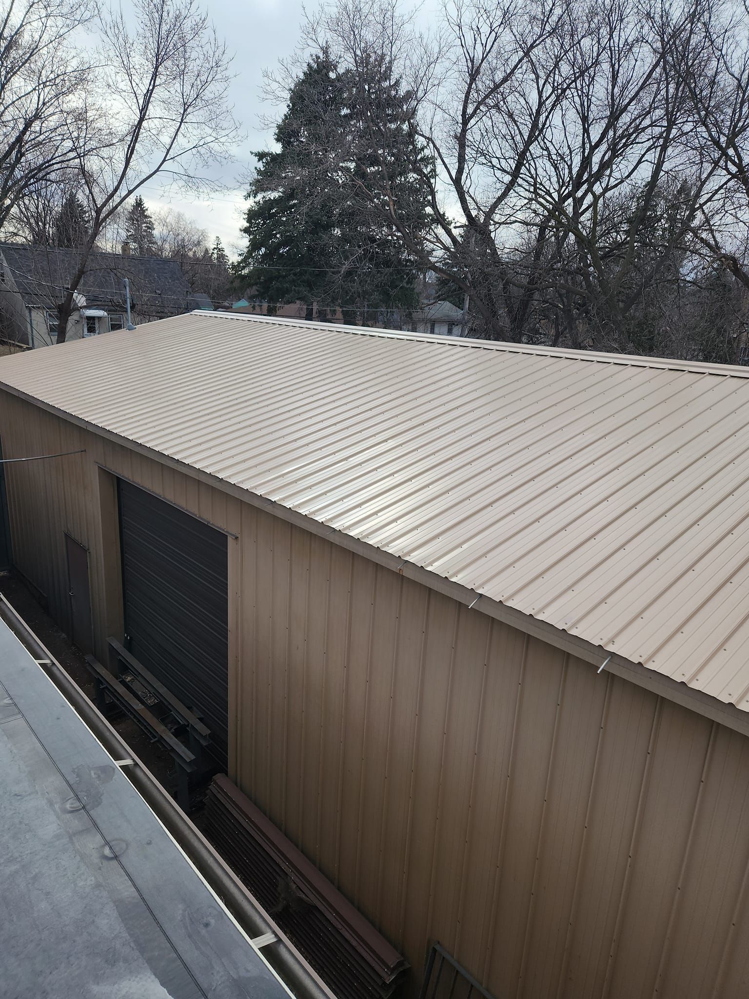 A building with a metal roof and trees in the background.