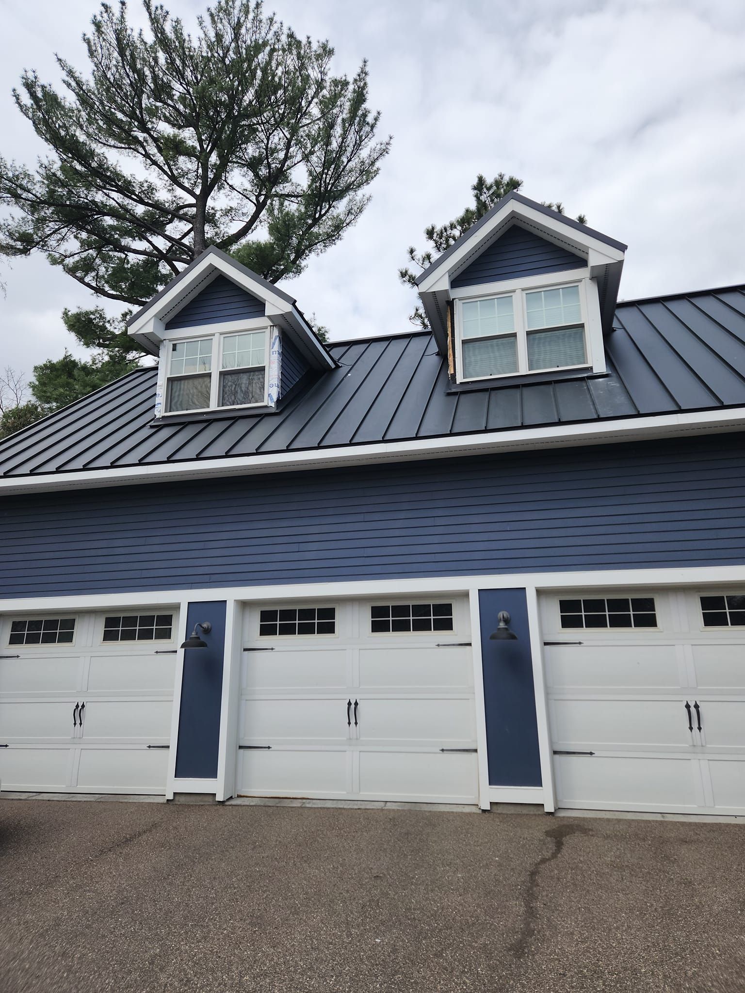 A blue house with white garage doors and a metal roof