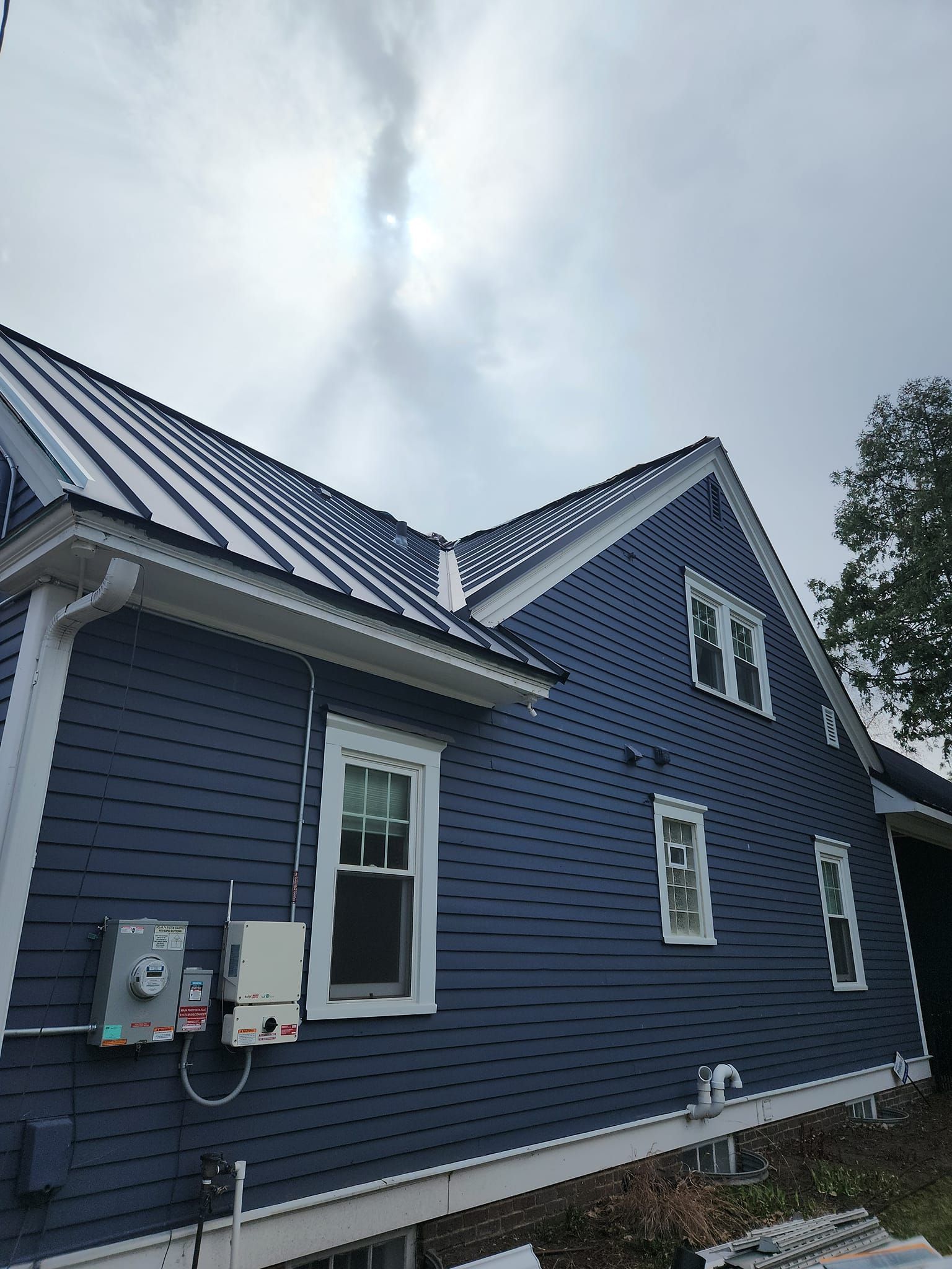 A blue house with a white trim and a metal roof.