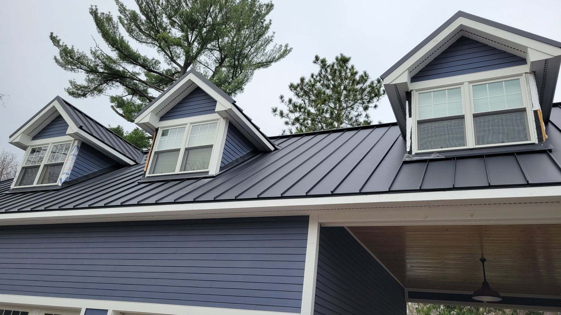 A blue house with a black roof and three windows.