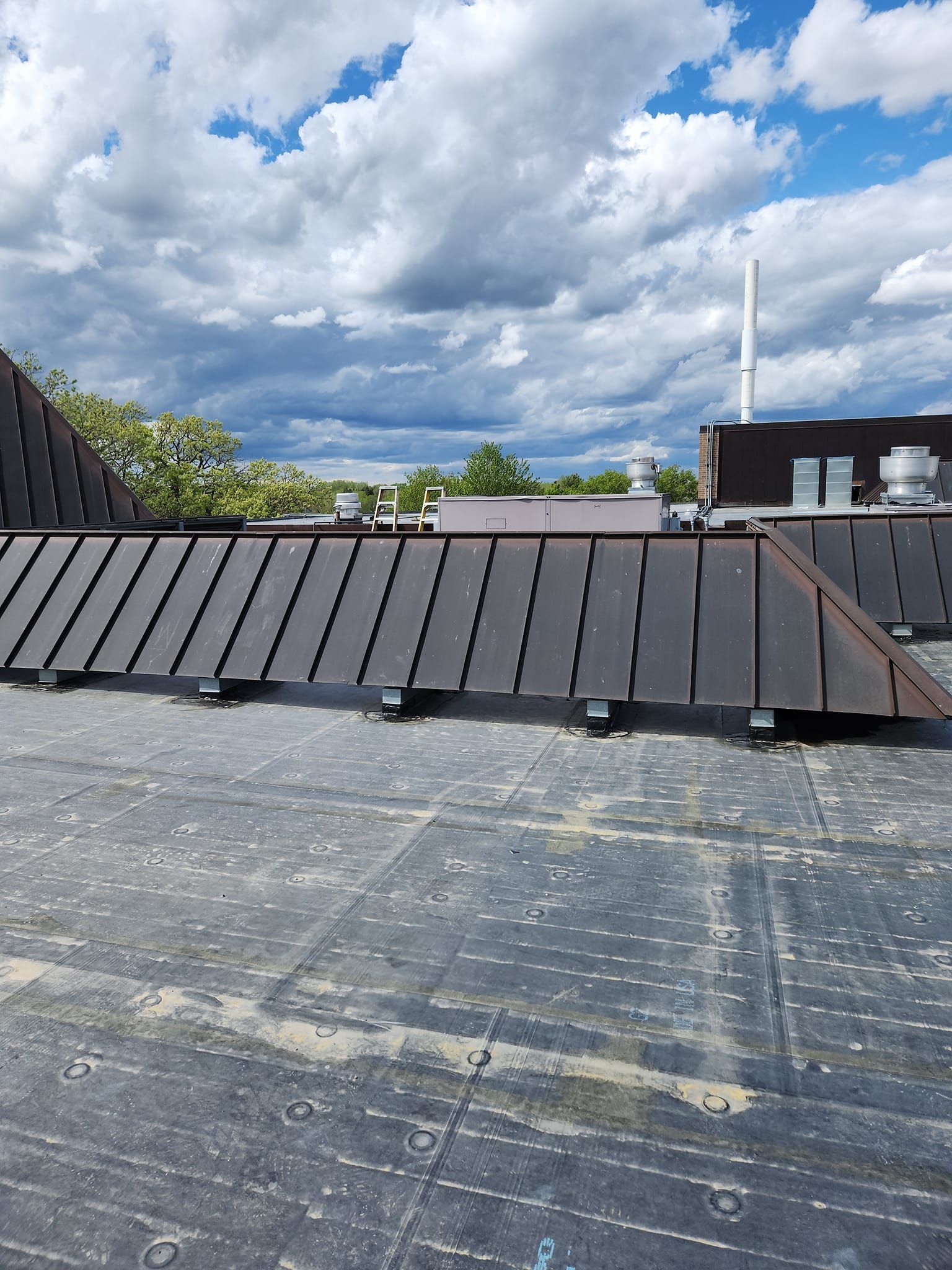 The roof of a building with a blue sky and clouds in the background