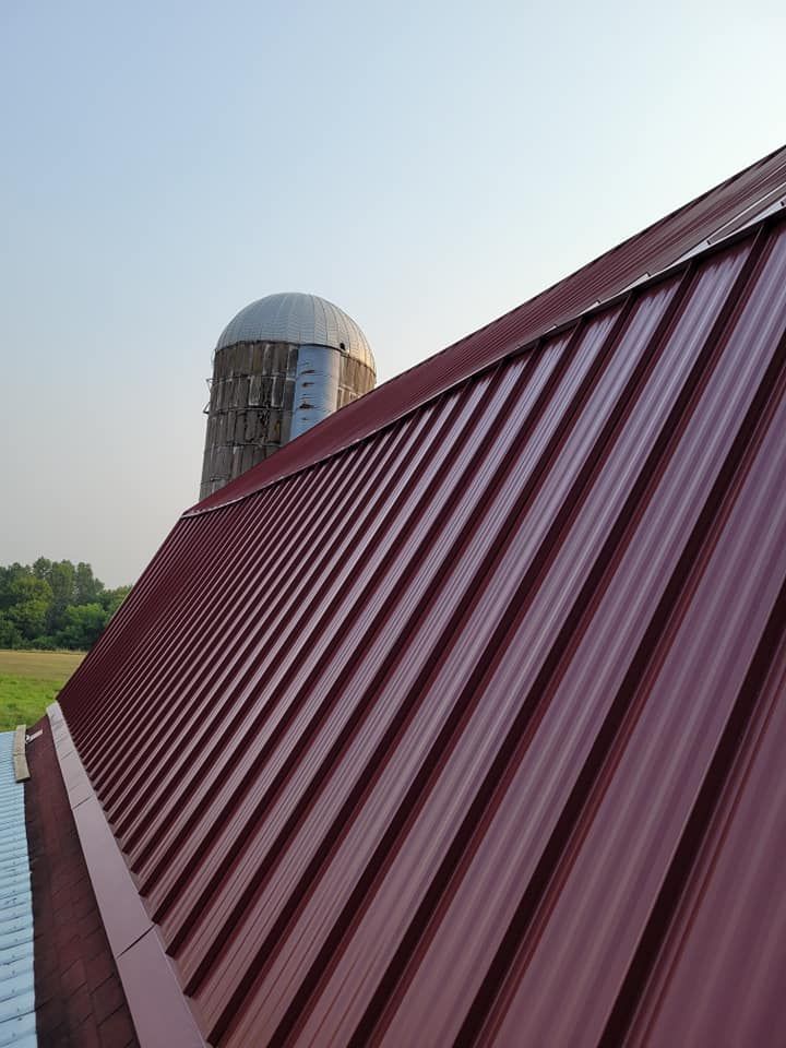 A red metal roof with a silo in the background.