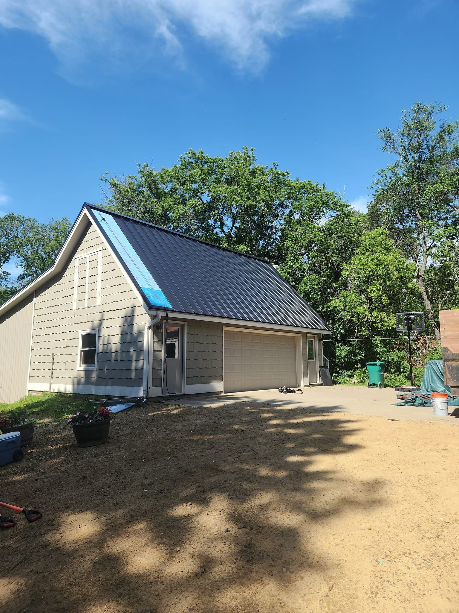 A house with a blue tarp on the roof is being built.