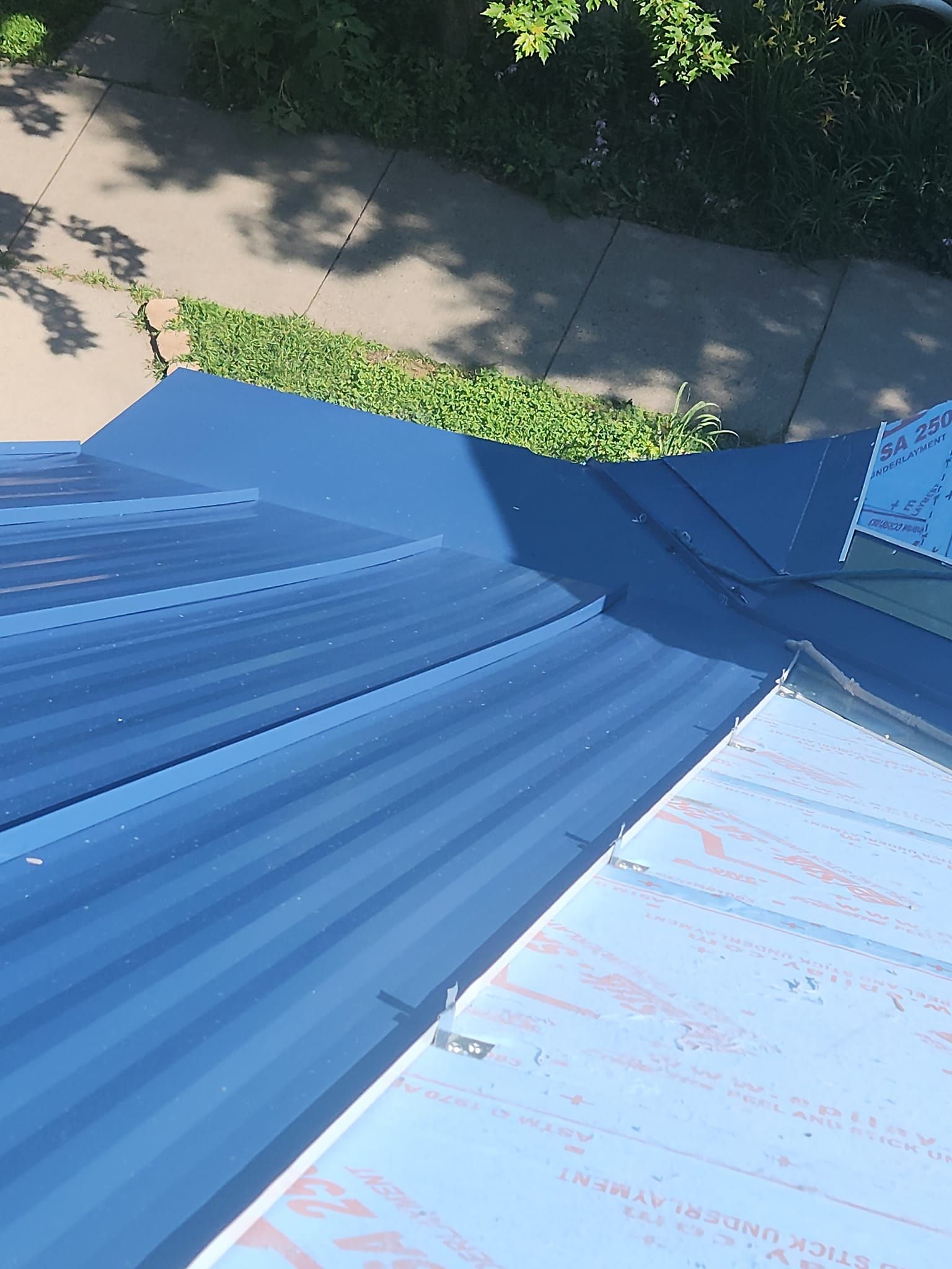 A blue roof is sitting on top of a sidewalk next to a sidewalk.
