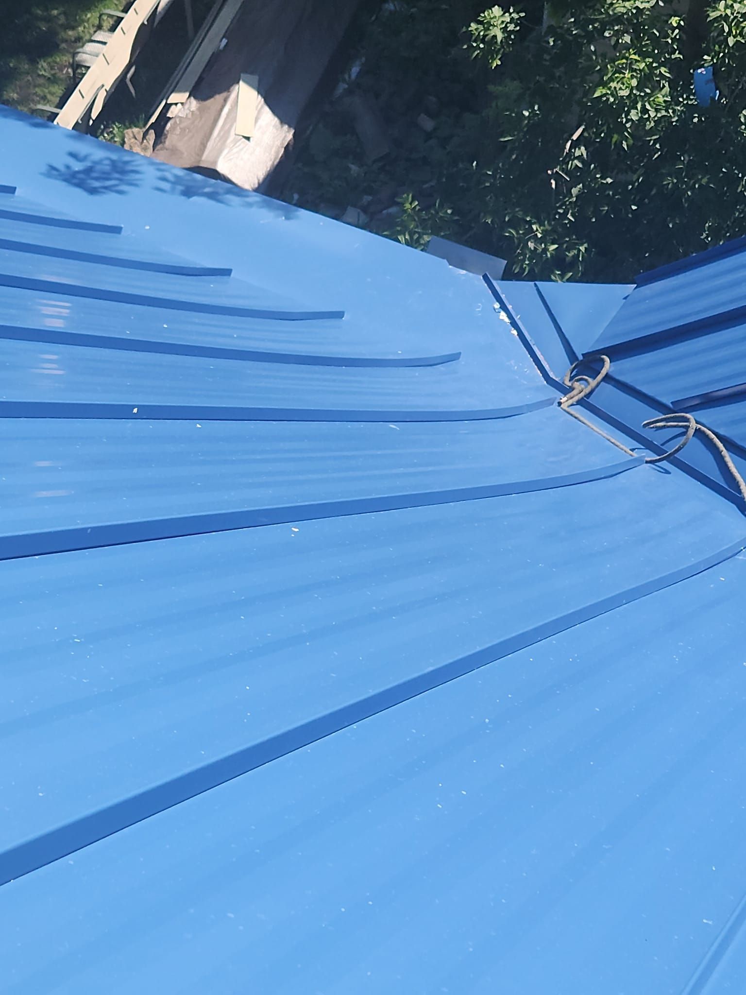 A close up of a blue roof with a rope attached to it.