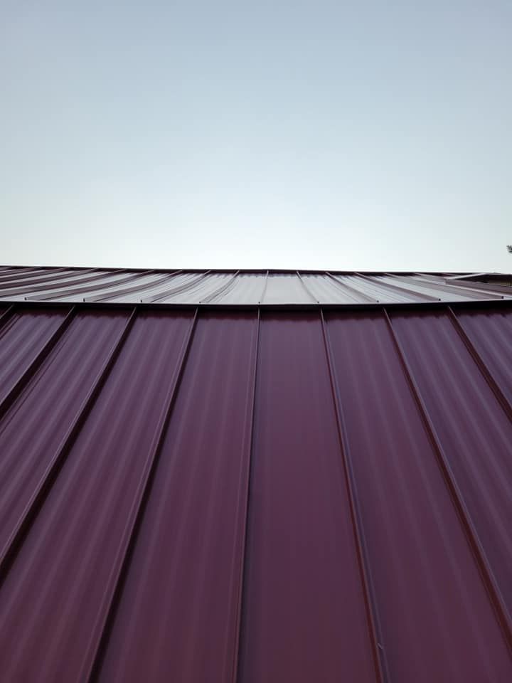 Looking up at a red metal roof with a blue sky in the background.