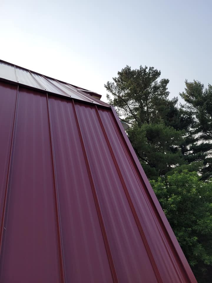 A red metal roof with trees in the background
