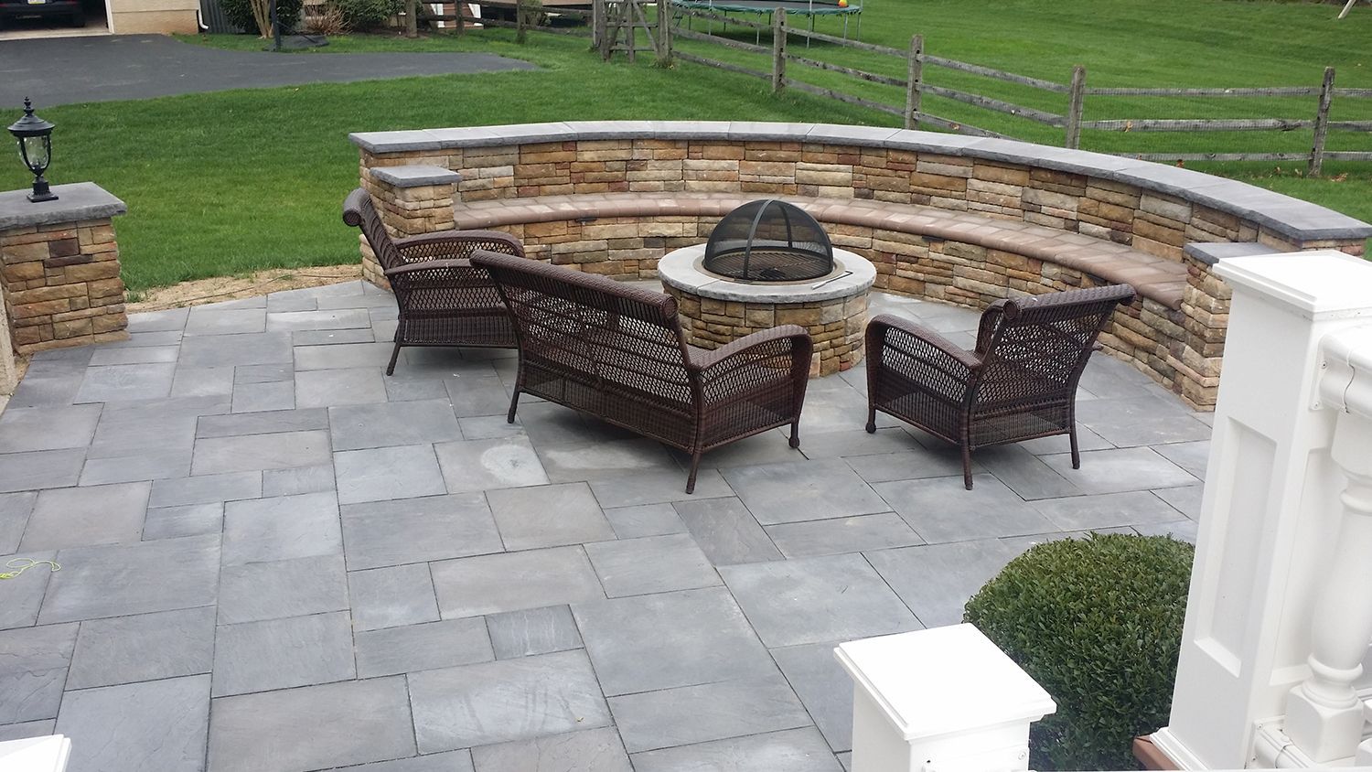Outdoor patio with stone seating, fireplace, and wicker furniture.