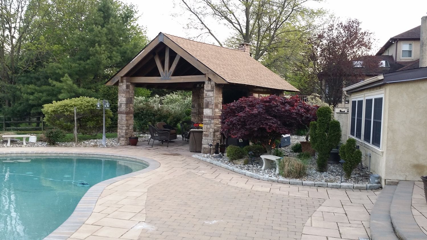 Poolside patio with stone pavilion and landscaping.