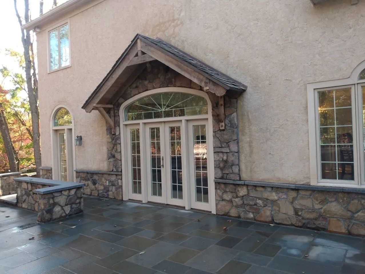 Exterior of a building with arched doors and windows, stone and stucco facade, and a patio.