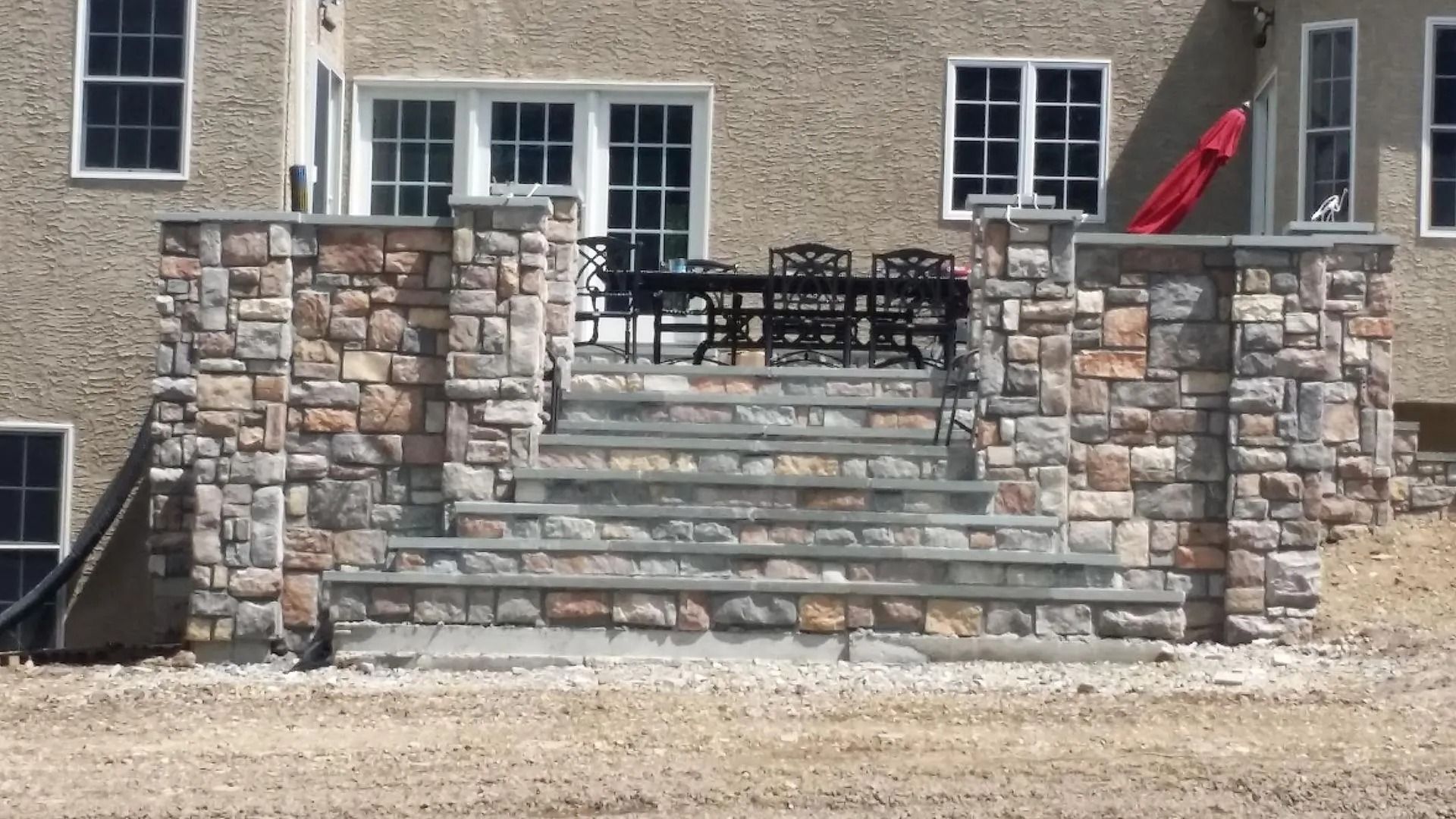 Stone steps and retaining walls leading to a patio with outdoor furniture.