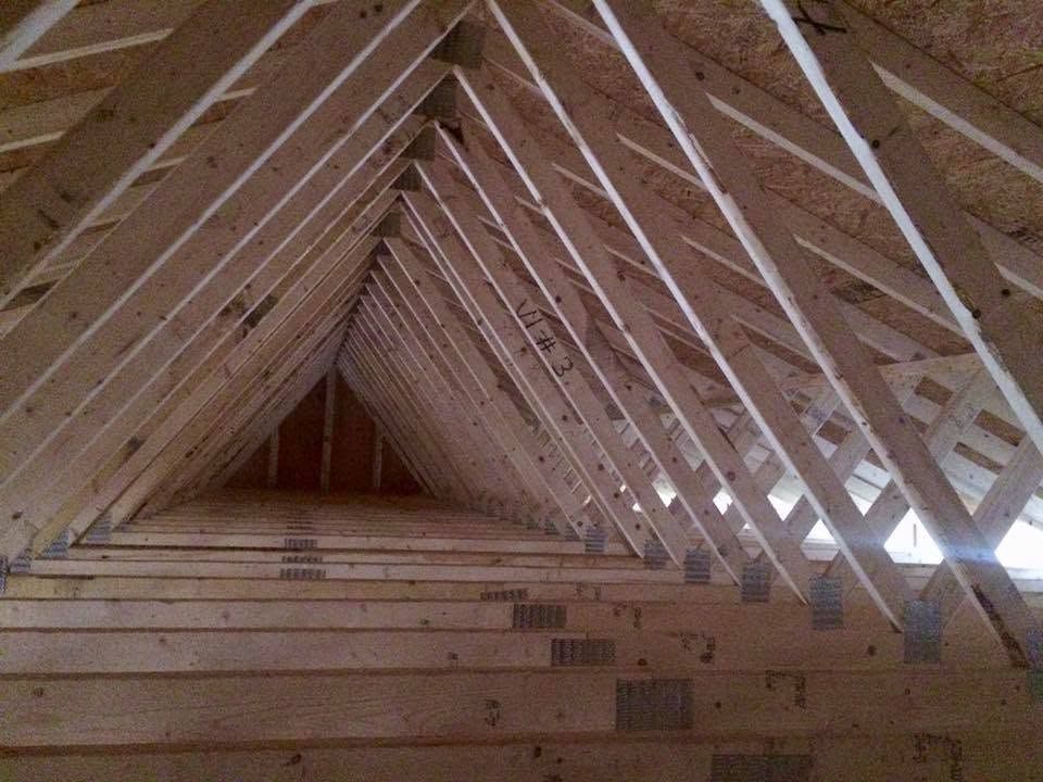 Interior of an unfinished wooden attic roof with exposed trusses and beams