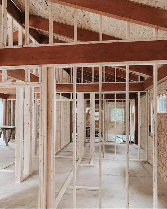 Interior of a house under construction with exposed wooden framing and unfinished walls