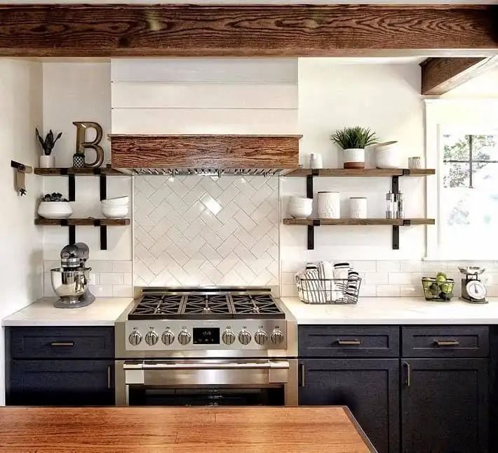 Bright modern kitchen with stainless stove, white tile backsplash, dark cabinets, and open wood shelves
