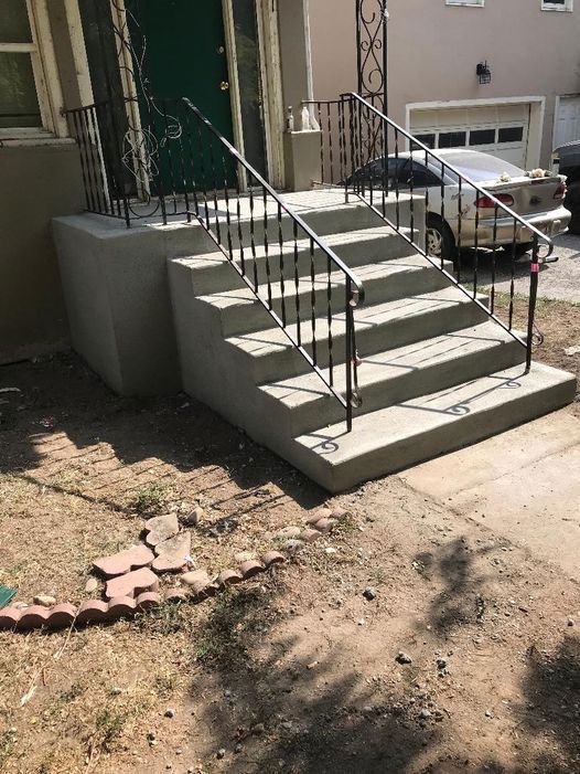 A set of stairs leading up to a house with a car parked in front of them.