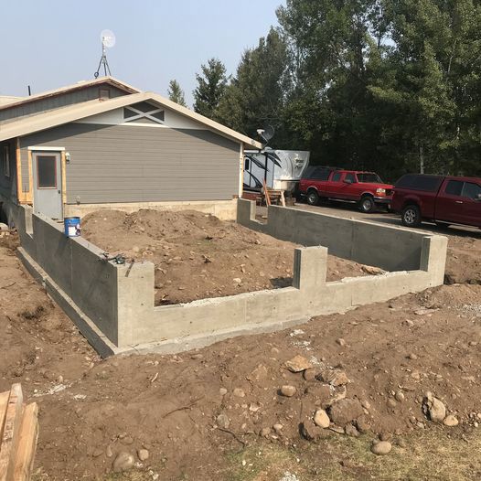 A red truck is parked in front of a house under construction