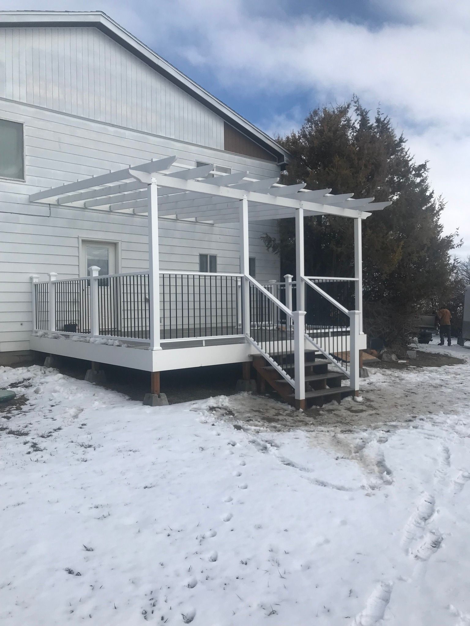 A white house with a porch and stairs in the snow