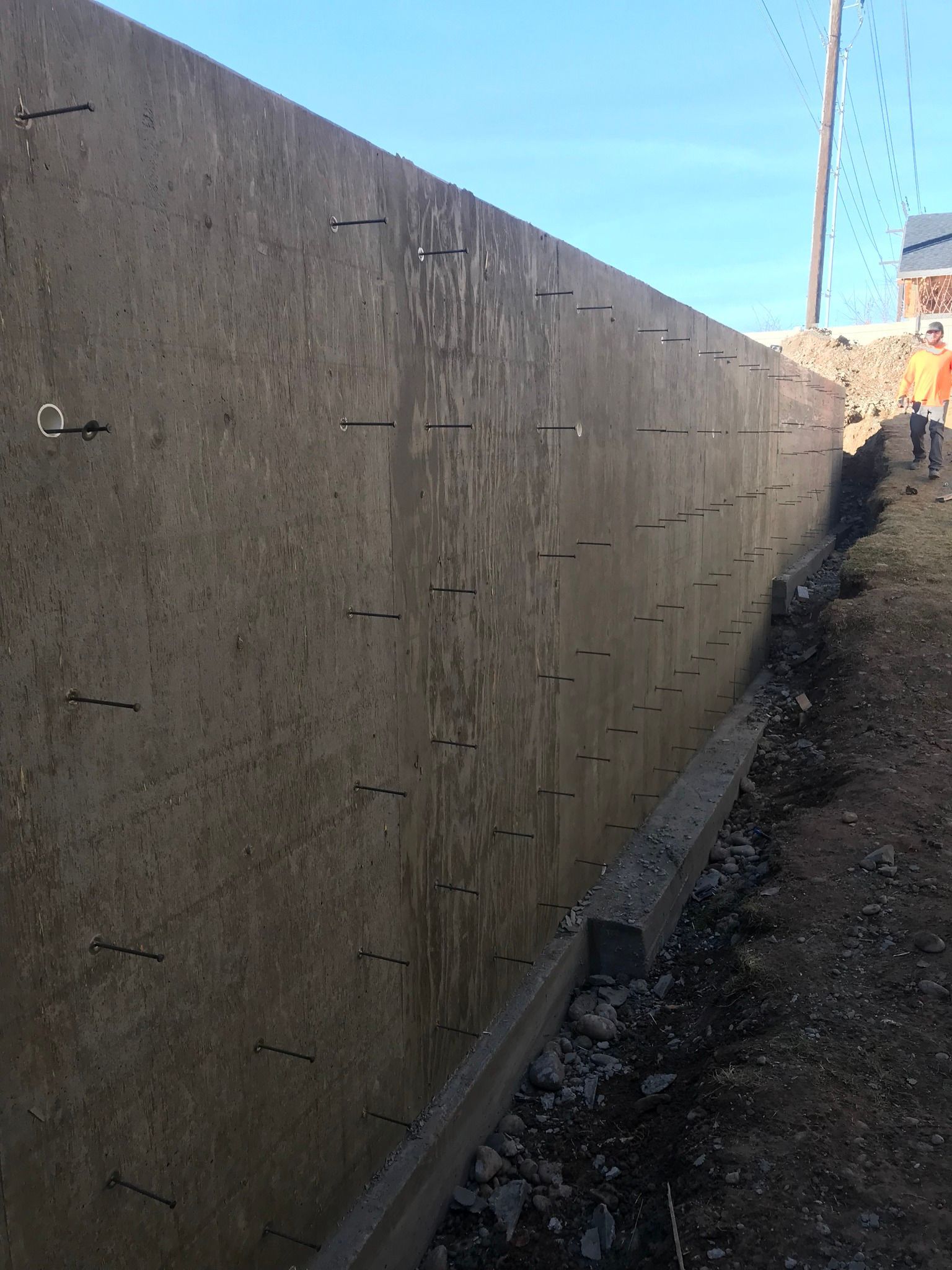 A man is standing next to a large concrete wall.