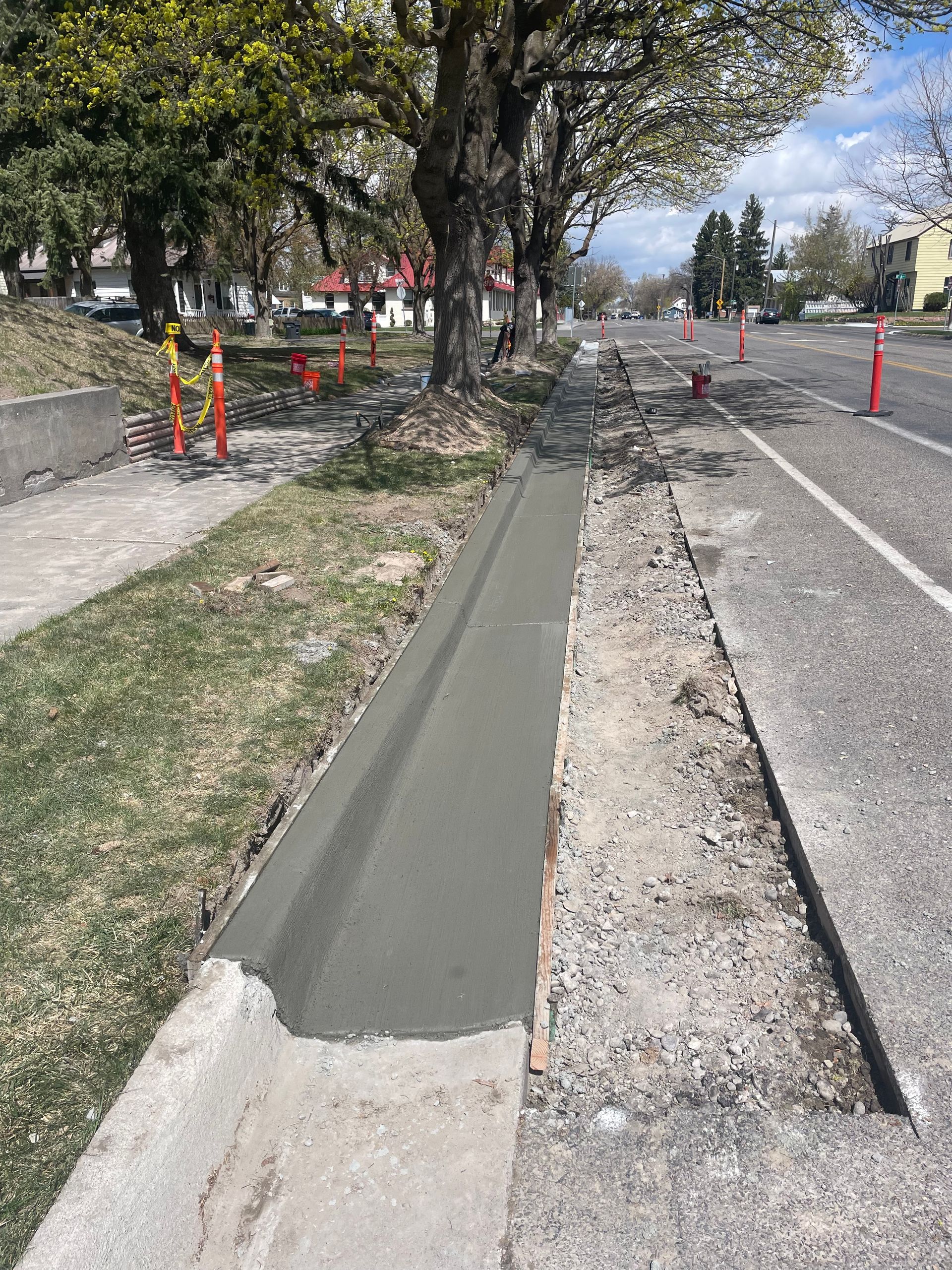 A concrete curb is being installed on the side of a road.