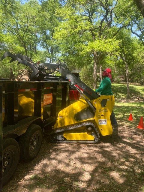Utility track loader loading a piece of wood into a truck.