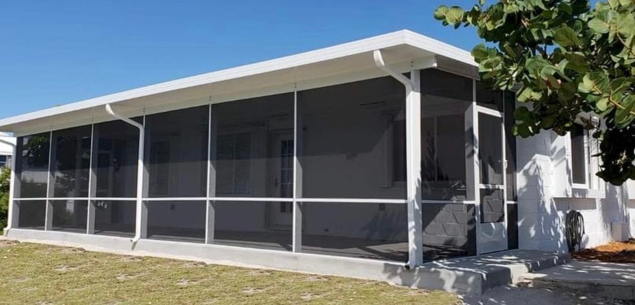 A white house with a screened in porch on the side of it.