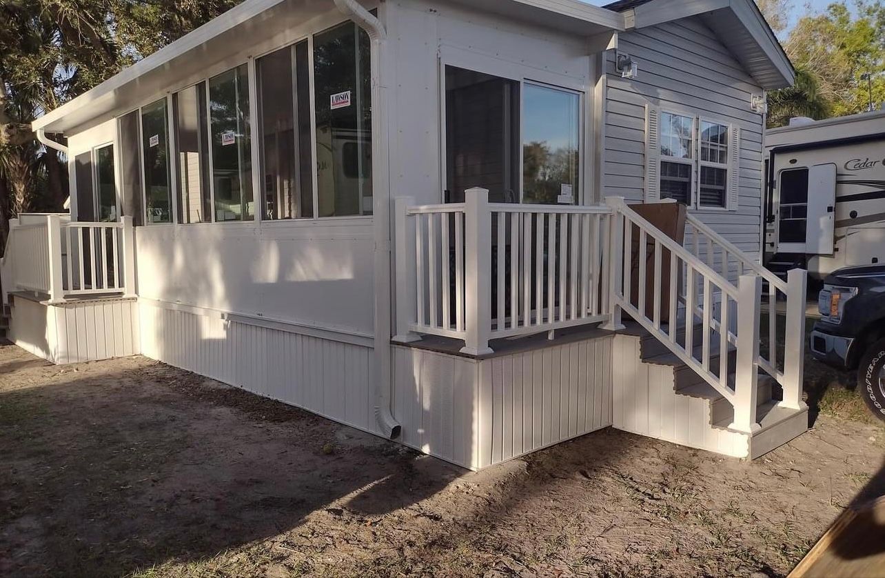 A white mobile home with a white railing and stairs.