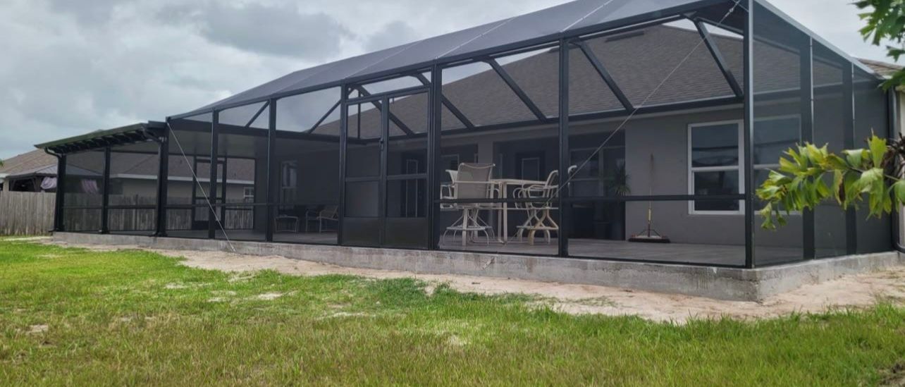 The back of a house with a screened in porch and patio.