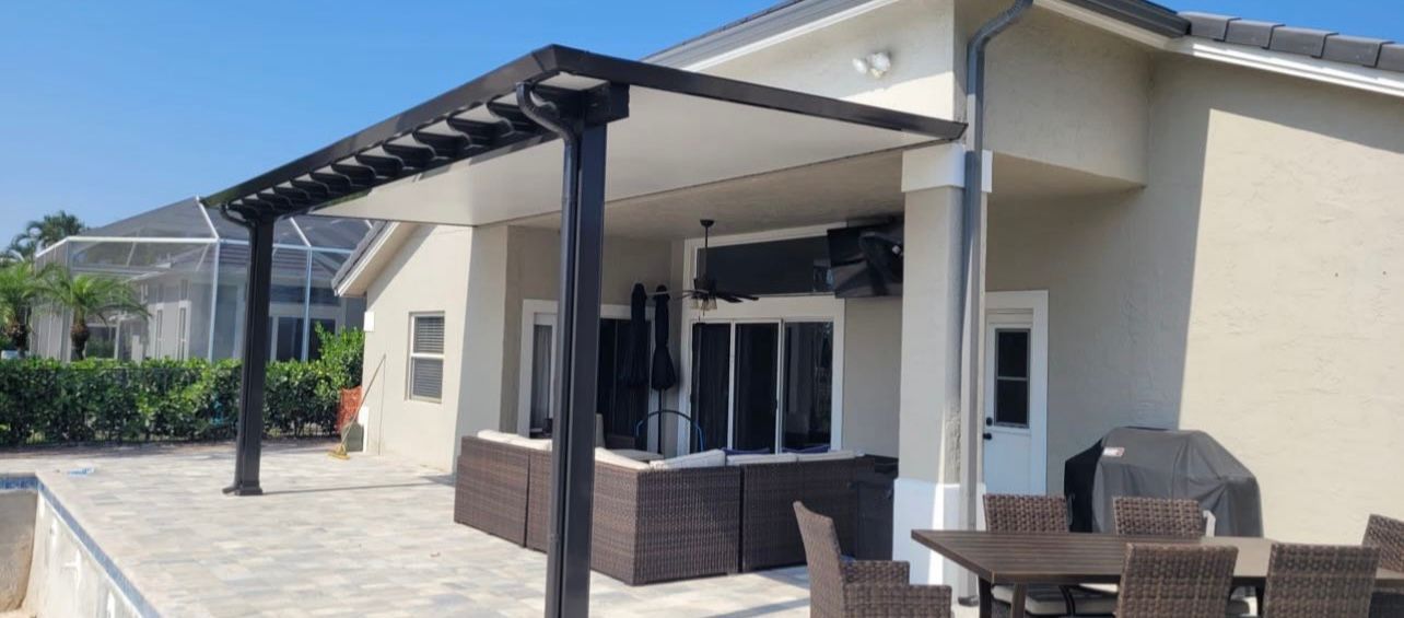 A house with a pergola and a patio with a table and chairs.