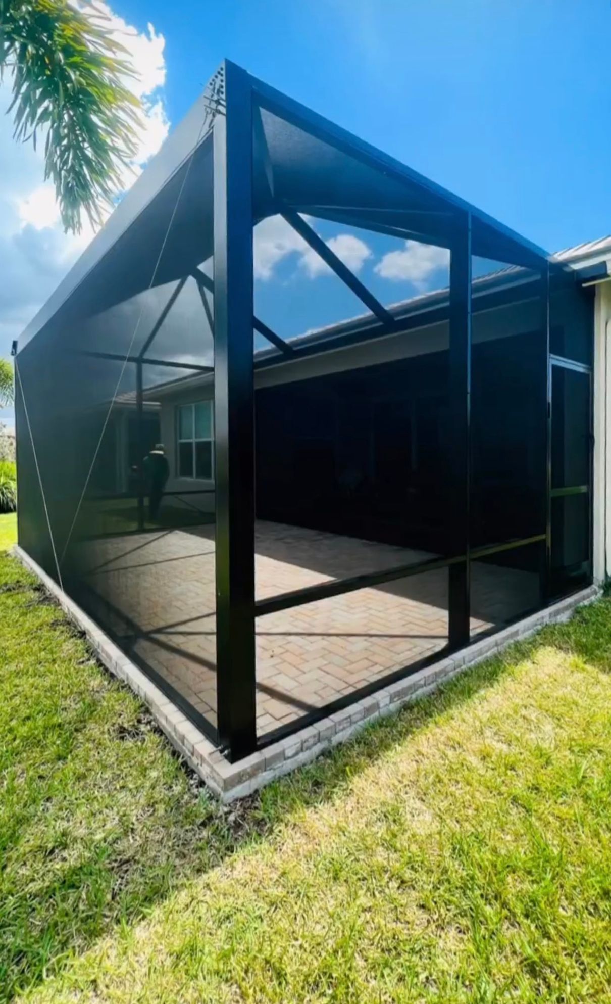 A screened in porch in the backyard of a house.