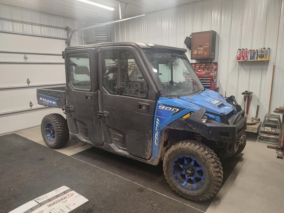 Dark blue and black Polaris Ranger utility vehicle parked inside a garage.