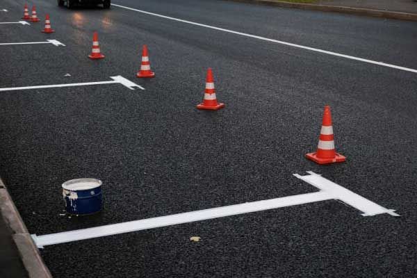A row of orange and white traffic cones on the side of a road.