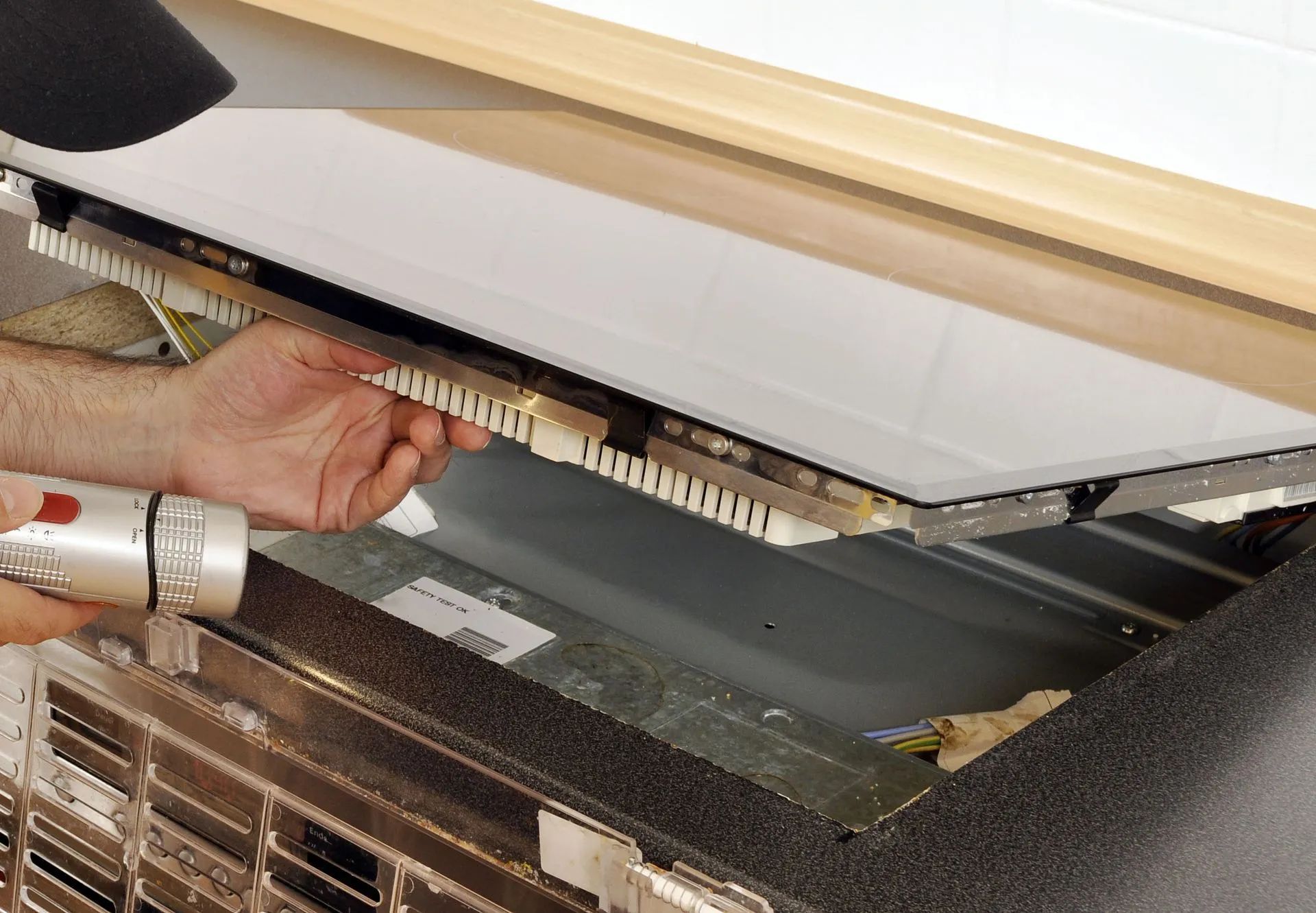 Person using a drill to install a panel, likely part of an appliance or display.
