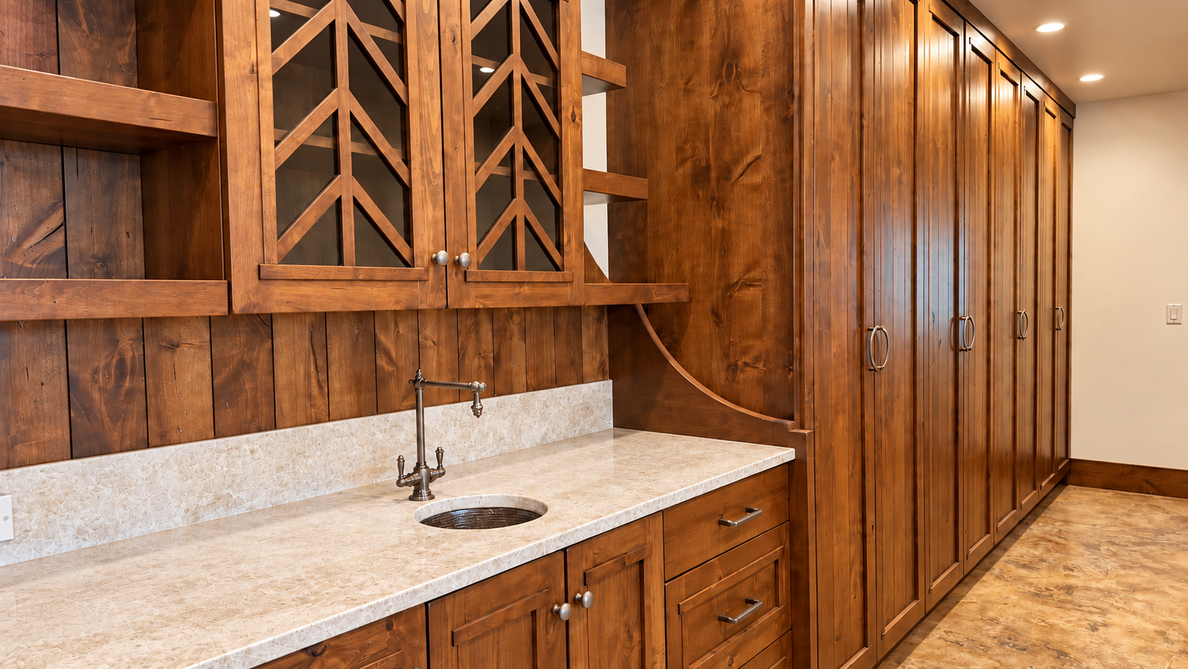 Wood-paneled kitchen with granite countertop, sink, cabinets, and built-in wine storage nook