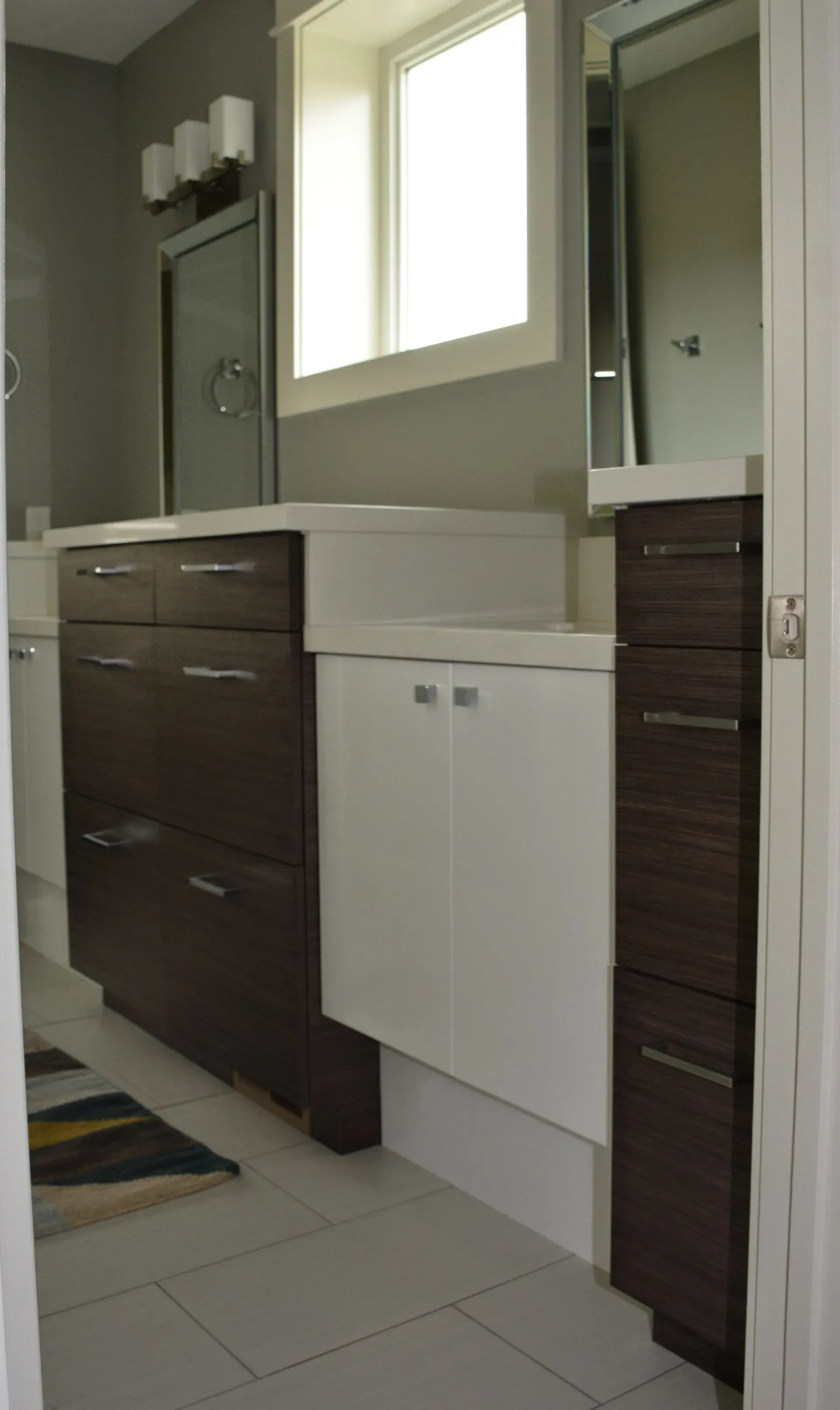A bathroom vanity featuring a dark wood cabinet, a white middle cabinet, and a matching dark wood tall storage tower.