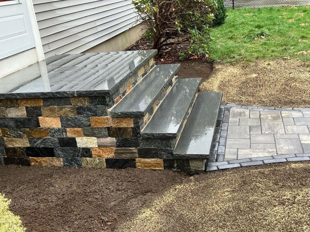 A set of stairs leading up to a house next to a stone wall.
