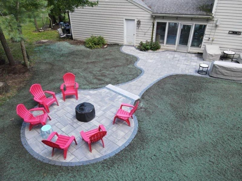 There is a fire pit in the middle of the patio with pink chairs.