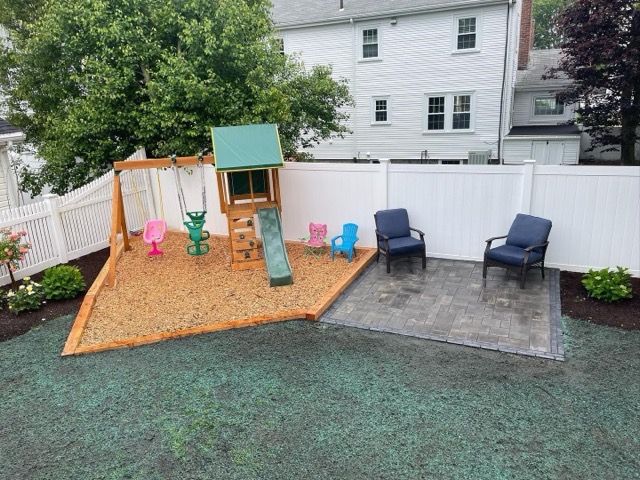 A backyard with a swing set , slide , and chairs.