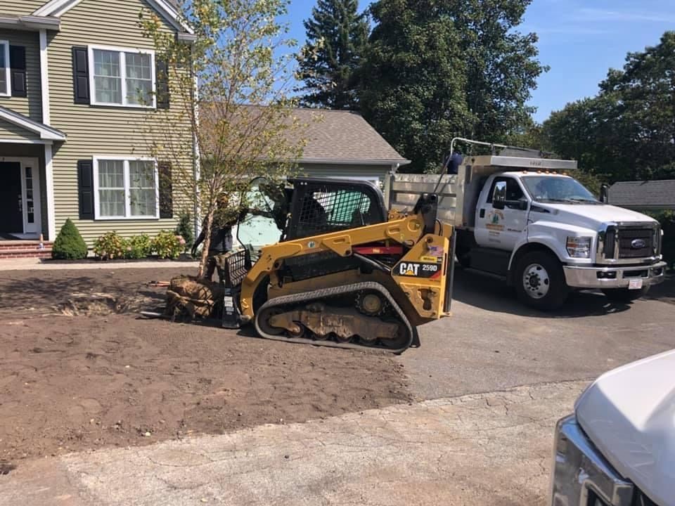 A bulldozer and a dump truck are parked in front of a house.