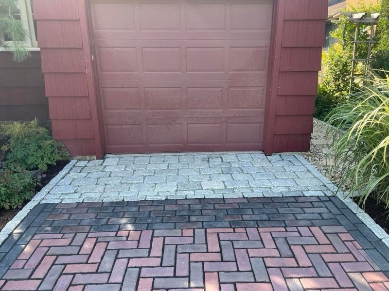 A brick driveway leading to a red garage door