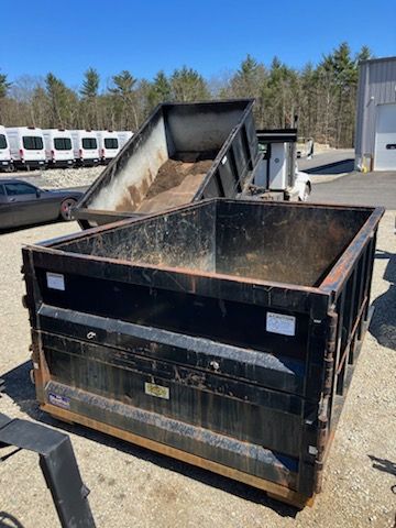 A dumpster is sitting on the ground in a parking lot.