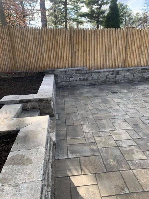 A brick patio with a wooden fence in the background.