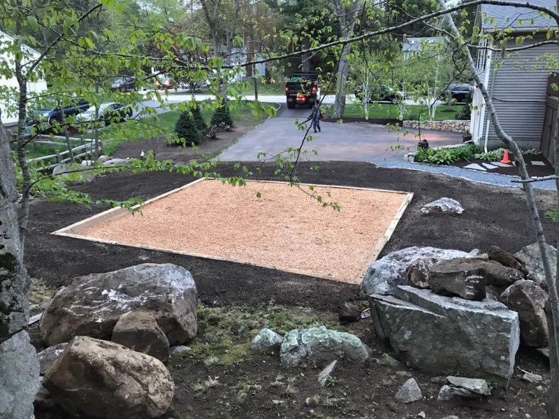 A large rock in the middle of a yard next to a house.