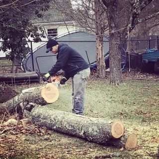 A man is cutting a log with a chainsaw.