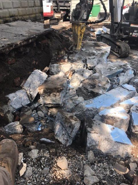 A pile of rocks on the ground with a yellow excavator in the background