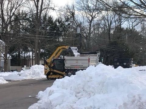 A dump truck is driving through a pile of snow.