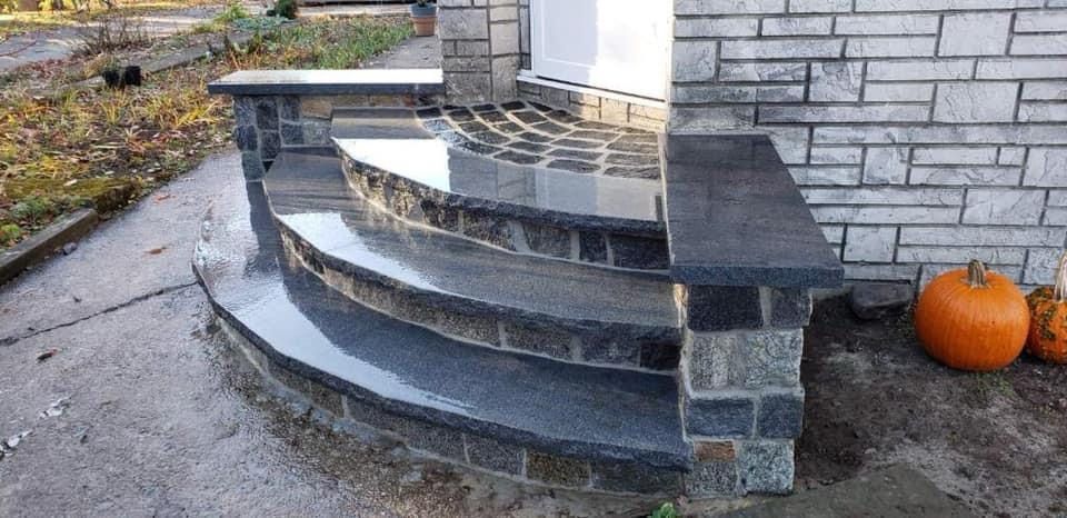 A set of stairs next to a brick building with pumpkins on the sidewalk.