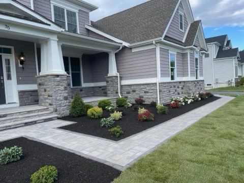 A house with a walkway leading to the front door and a lush green yard.
