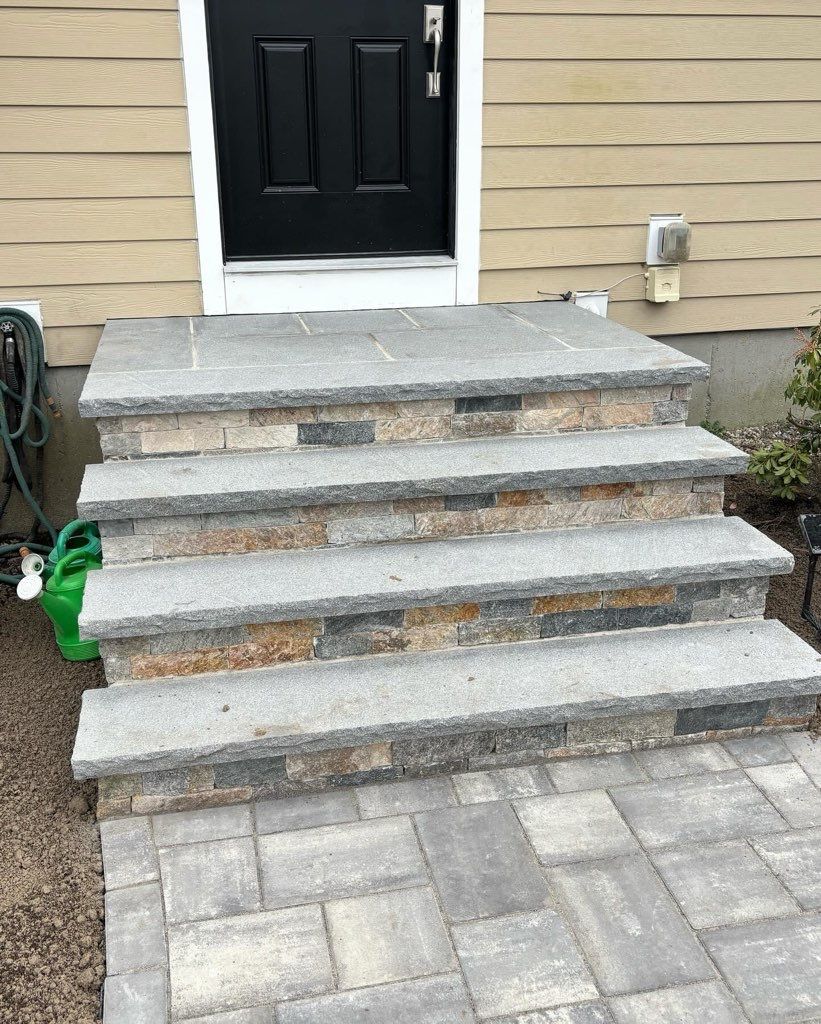 A set of stone steps leading up to a black door of a house.