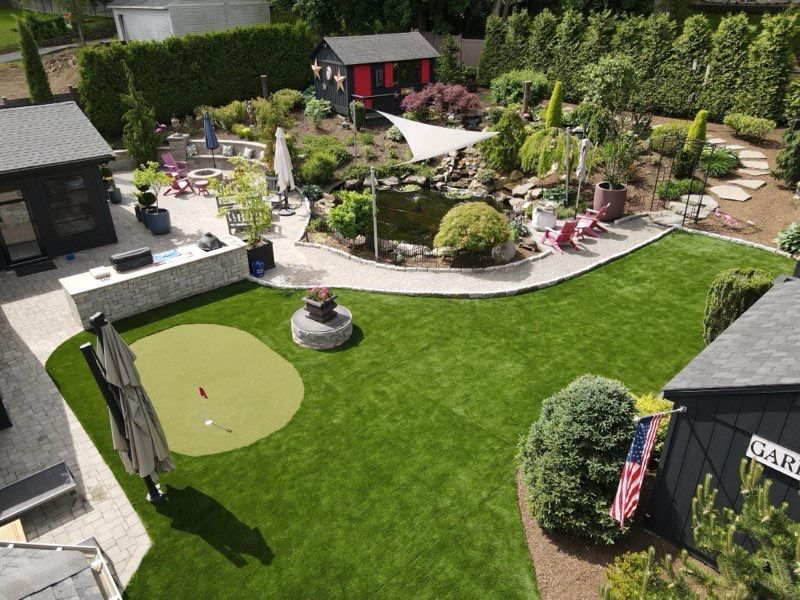 An aerial view of a lush green backyard with a putting green.